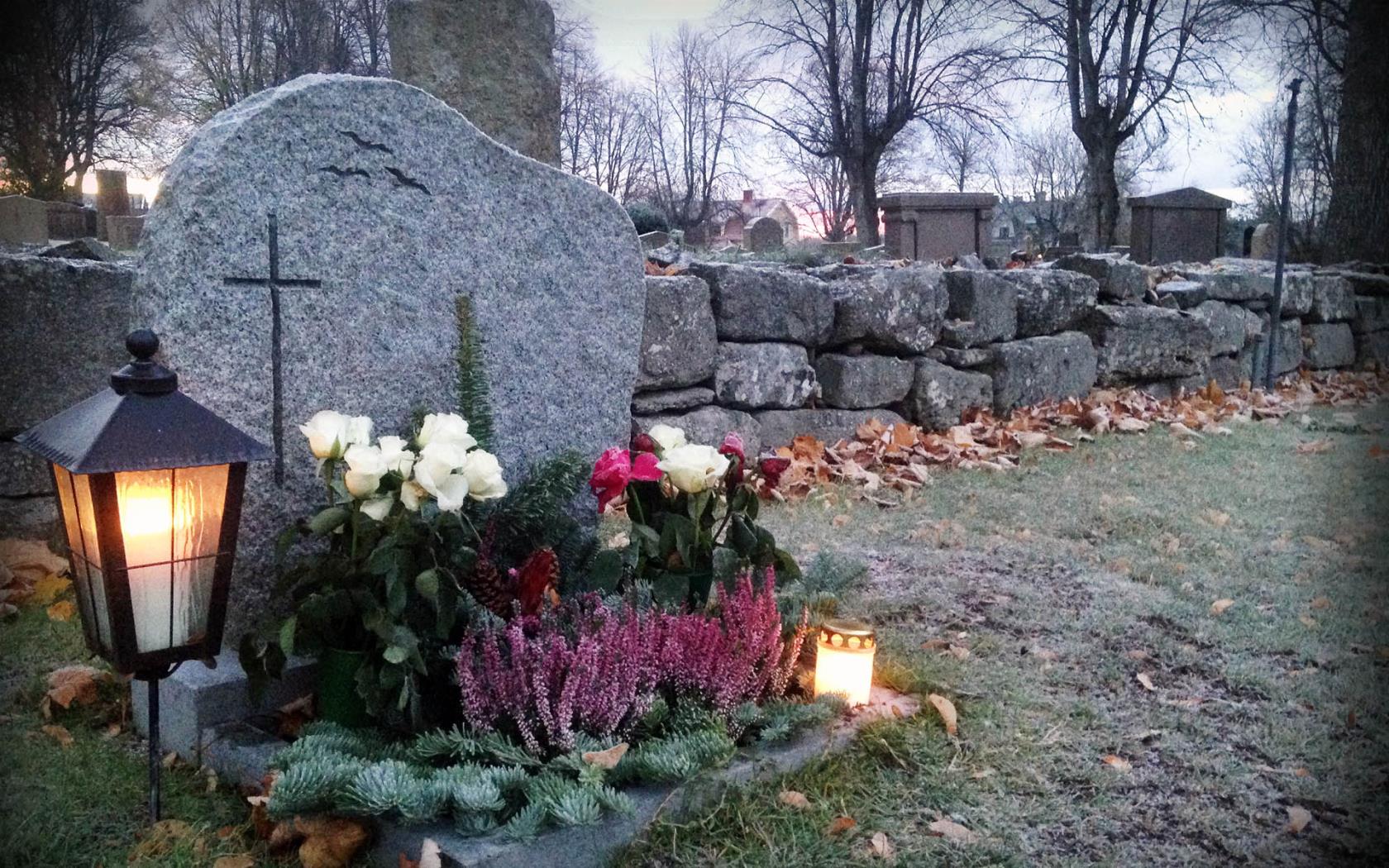 Smyckad grav med blommor och tända lyktor i allhelgonatid.