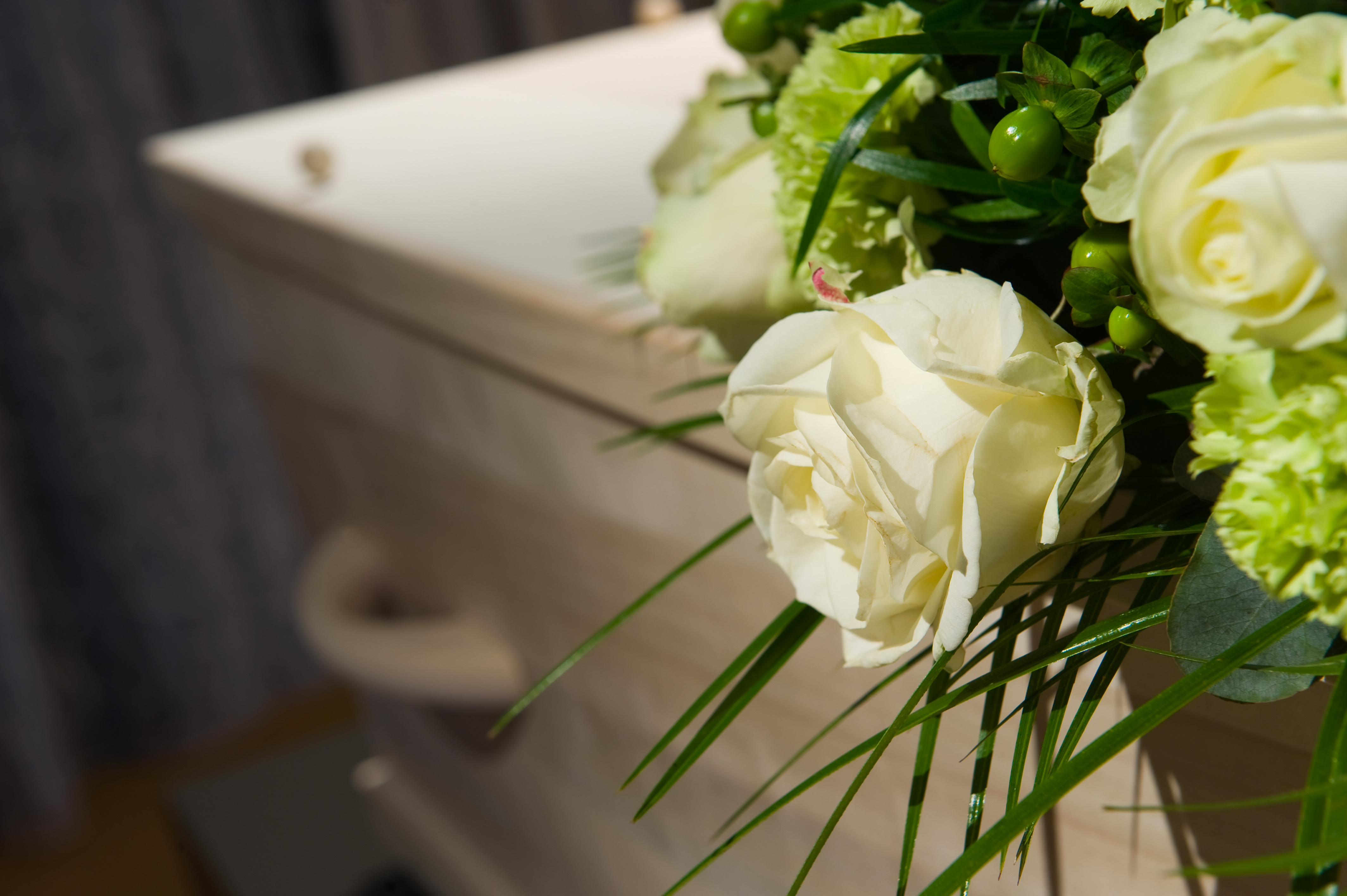 Begravningskista och bukett med vita rosor. 