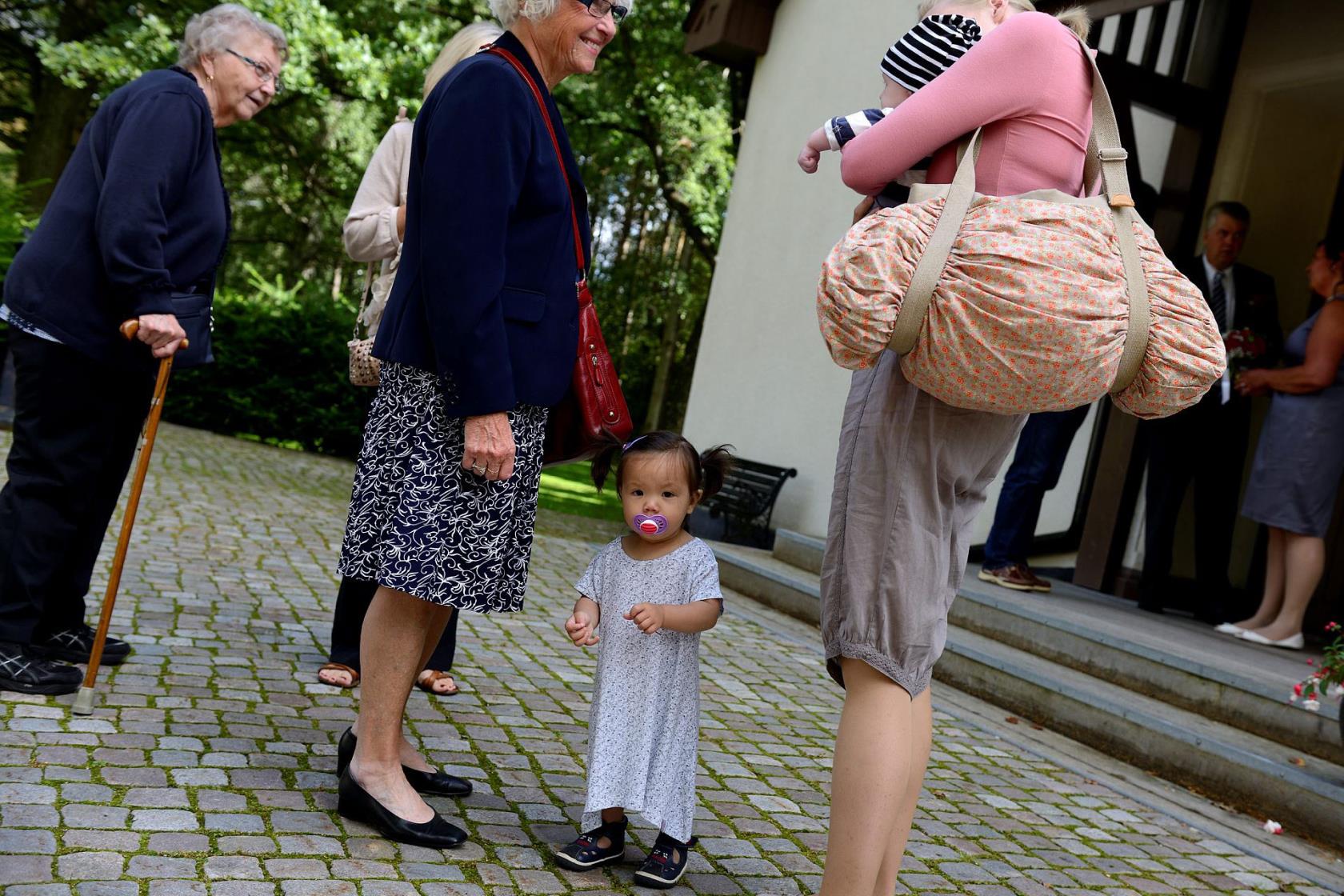 Gamla och unga samlas i vackert sommarväder utanför kyrkan.