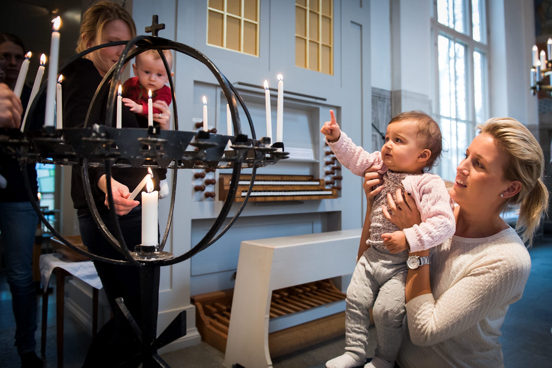 Mammor med sina barn tänder ljus i ljubäraren i kyrkan