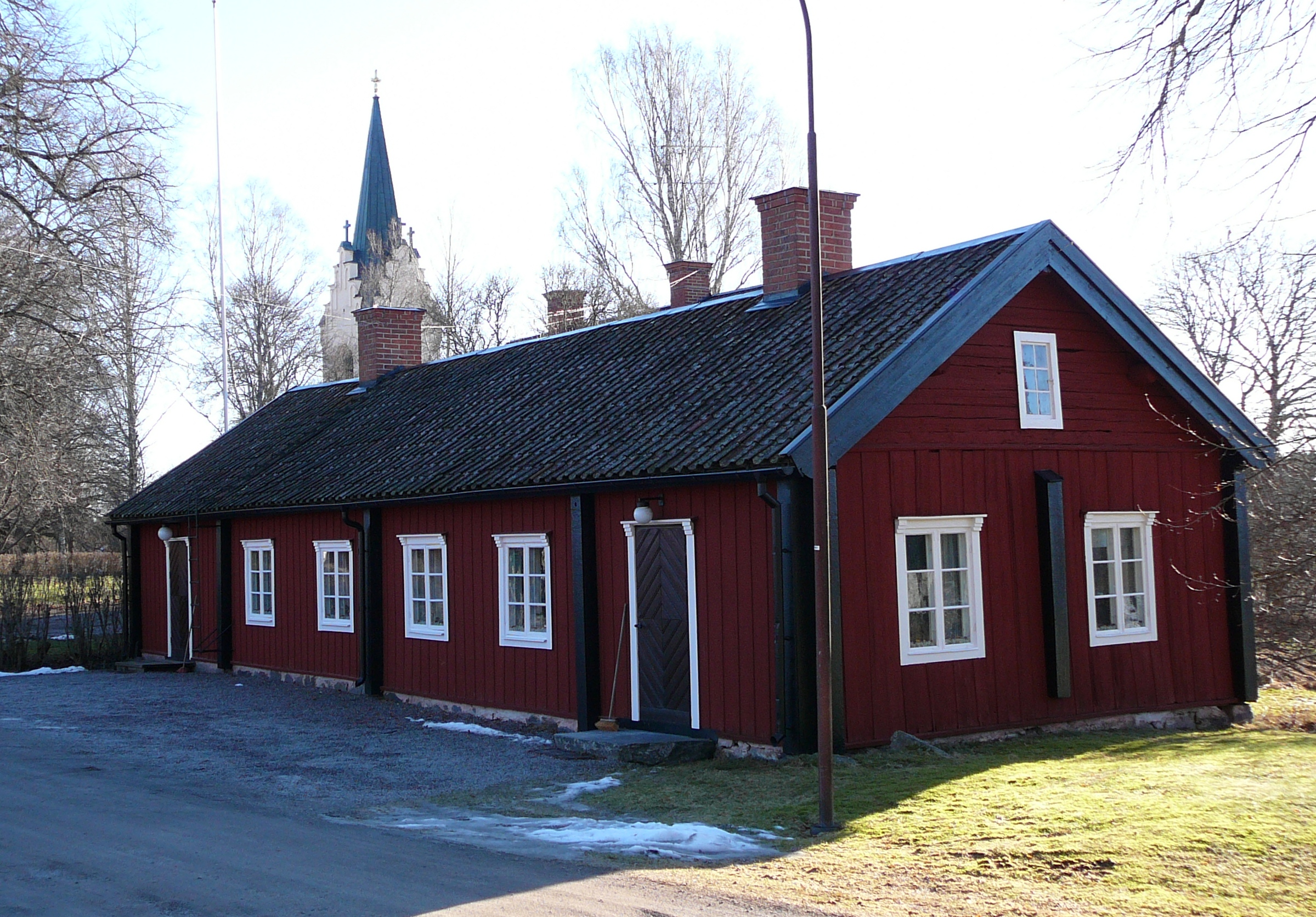 Mörkrött envåningshus med svarta knutar och vita fönsterfoder.