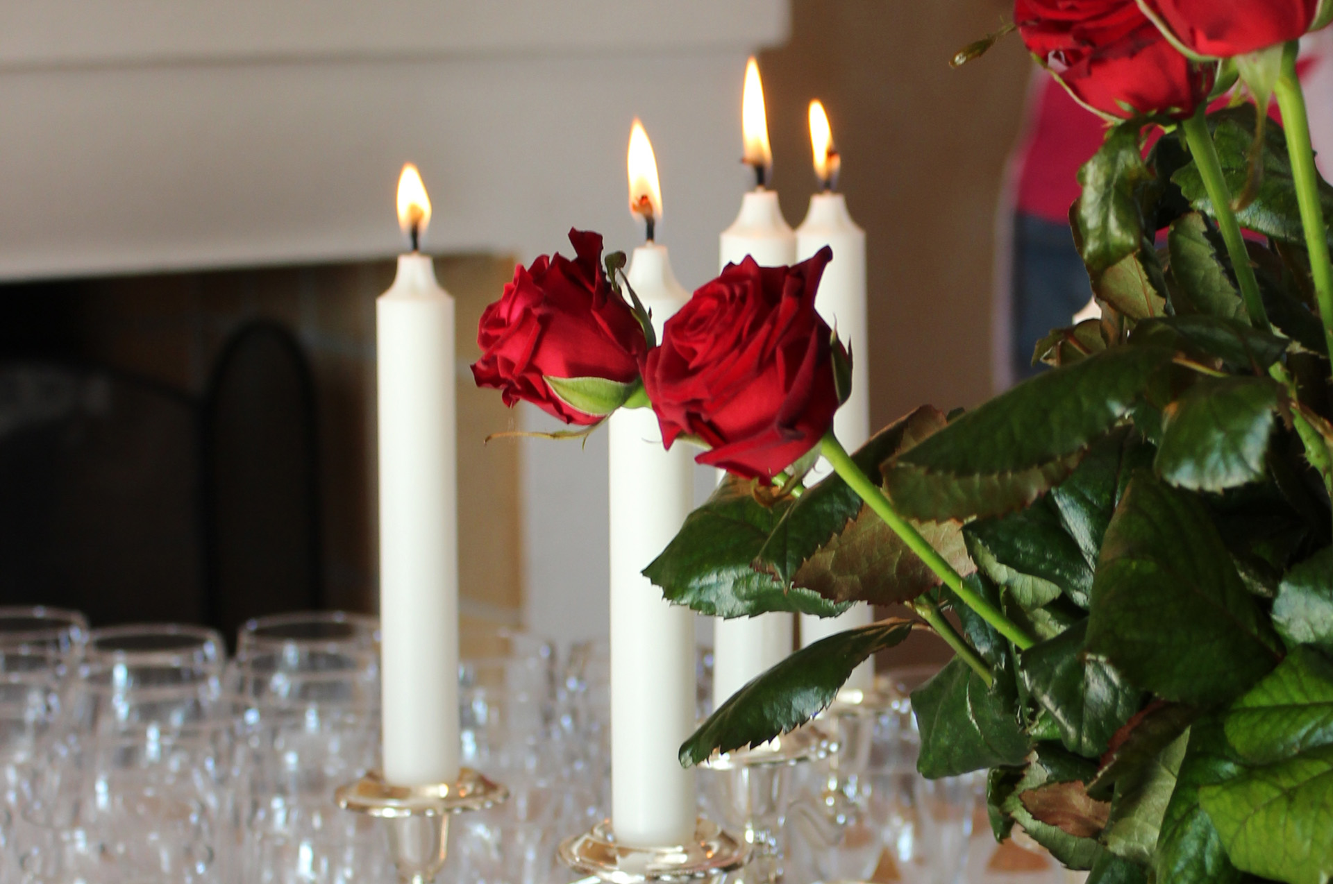 Levande ljus, röda rosor på ett bord.