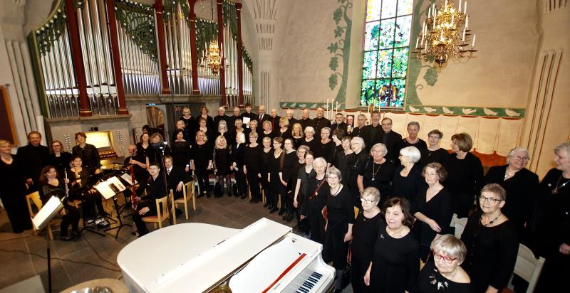 Bild på Backens kyrkokör och Hedlundakyrkans kammarkör framme vid ataret i Backens kyrka.