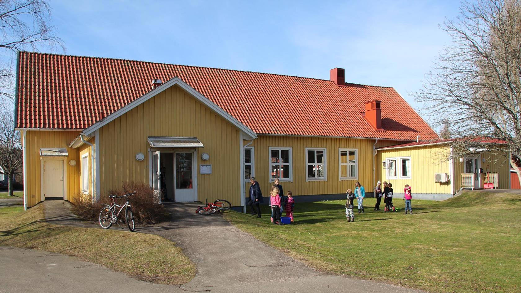 Fröjereds församlingshem och lägergård där några barn leker på gräsmattan, det är vår och solen skiner.