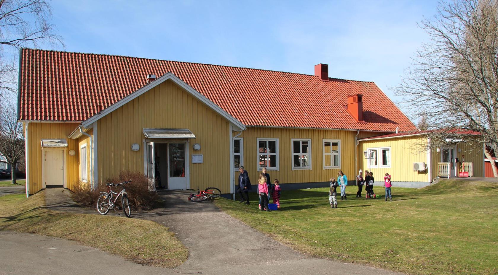 Fröjereds församlingshem och lägergård där några barn leker på gräsmattan, det är vår och solen skiner.