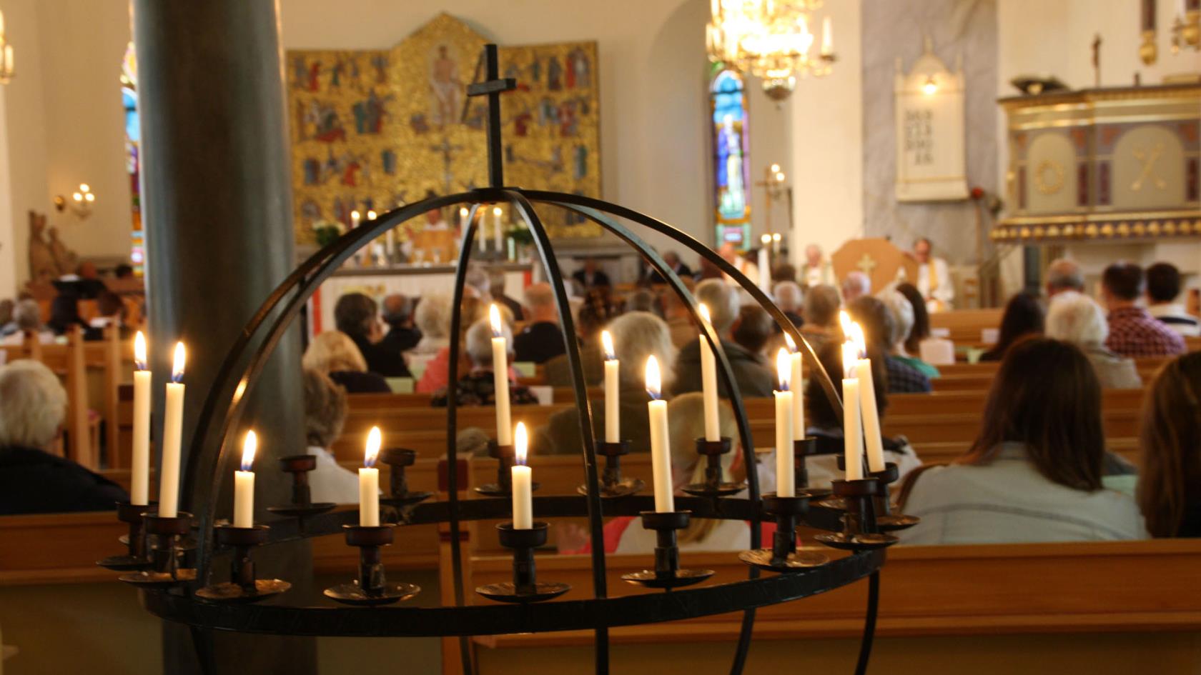 Ljusbärare i kyrka med församling i bakgrunden.