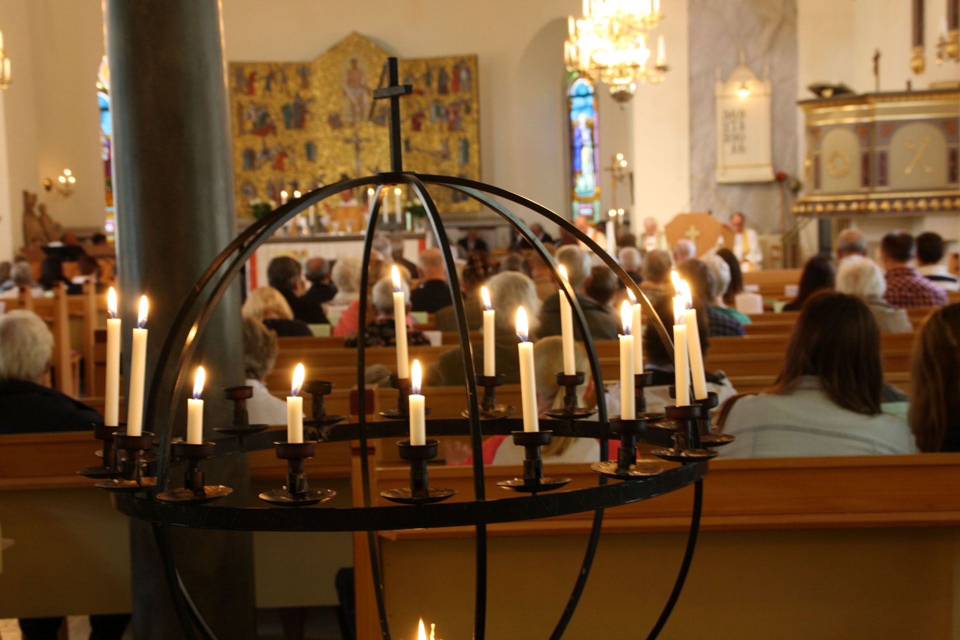 Ljusbärare i kyrka med församling i bakgrunden.