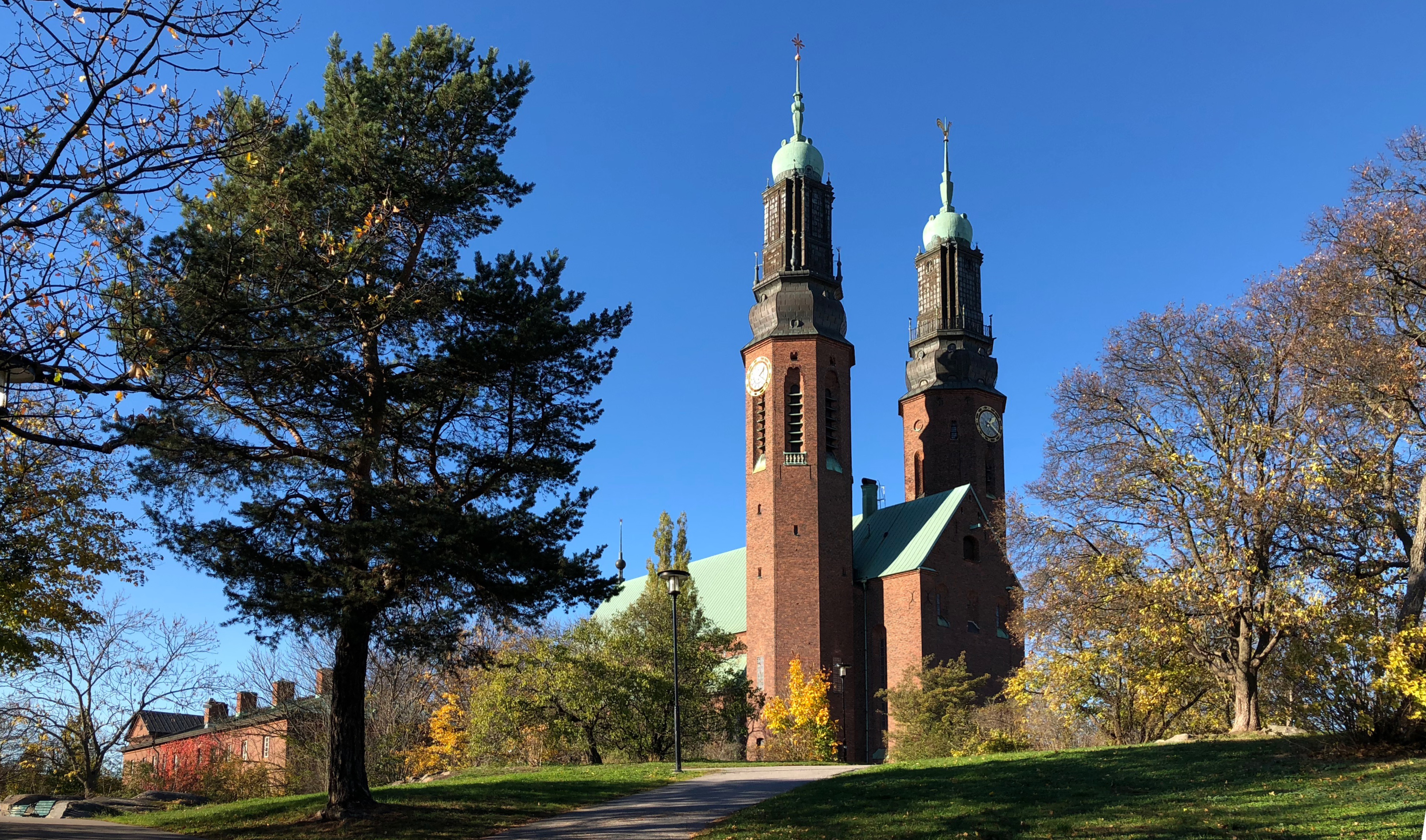 Högalidskyrkan med sina två torn, blå himmel och träd. Det ser ut att vara höst. 