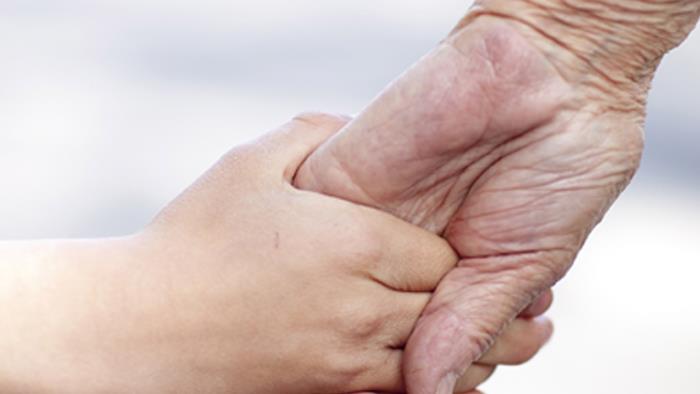 Barnhand som håller äldre hand