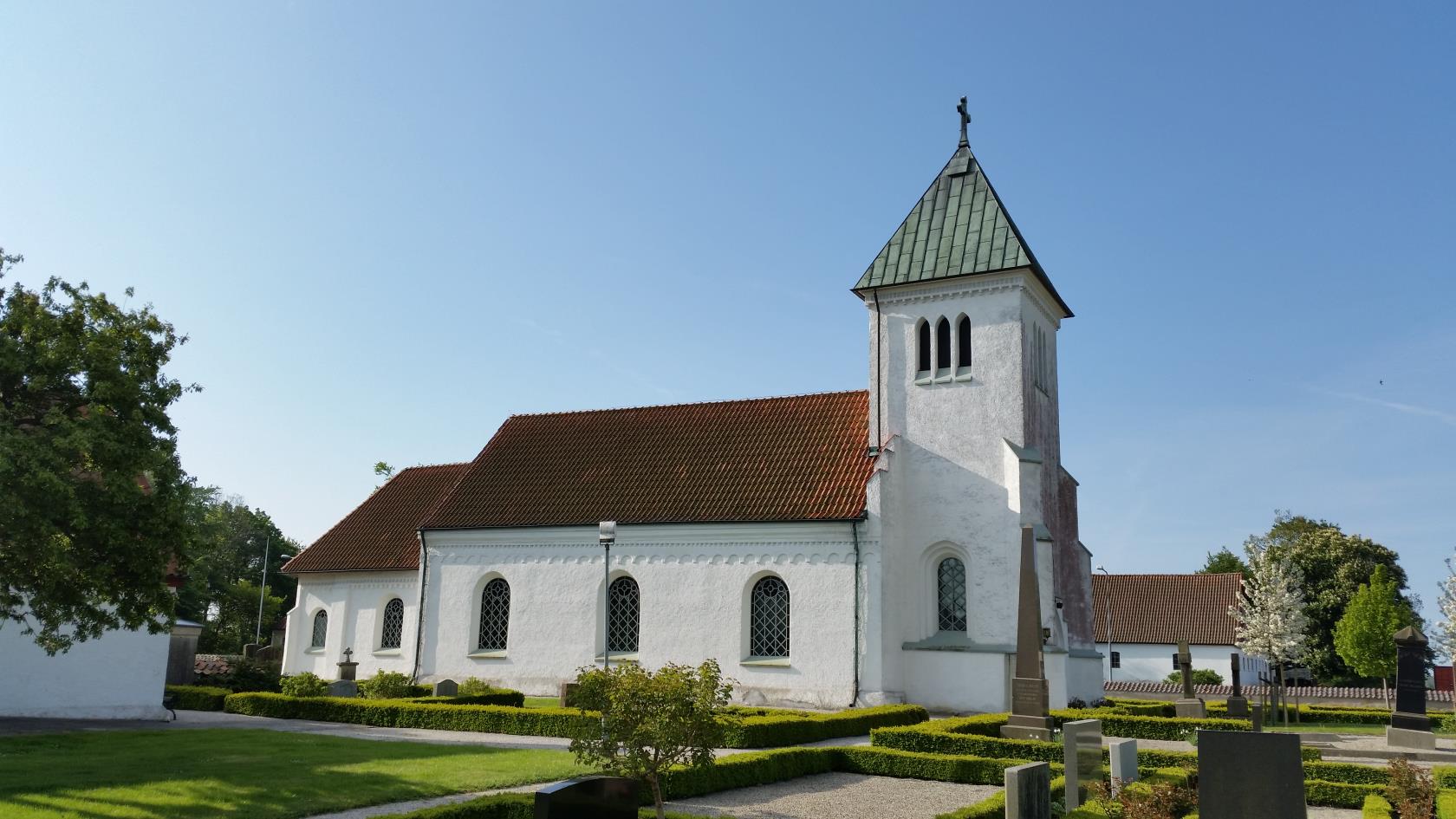 Vit kyrka med torn och rött tegeltak.