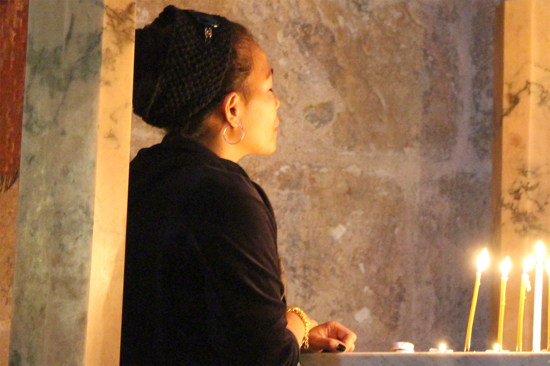 Kvinna i bön framför tända ljus
