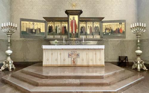 Altartavlan som Erik Jerkan gjorde, med altaret framför och ljus på var sin sida 