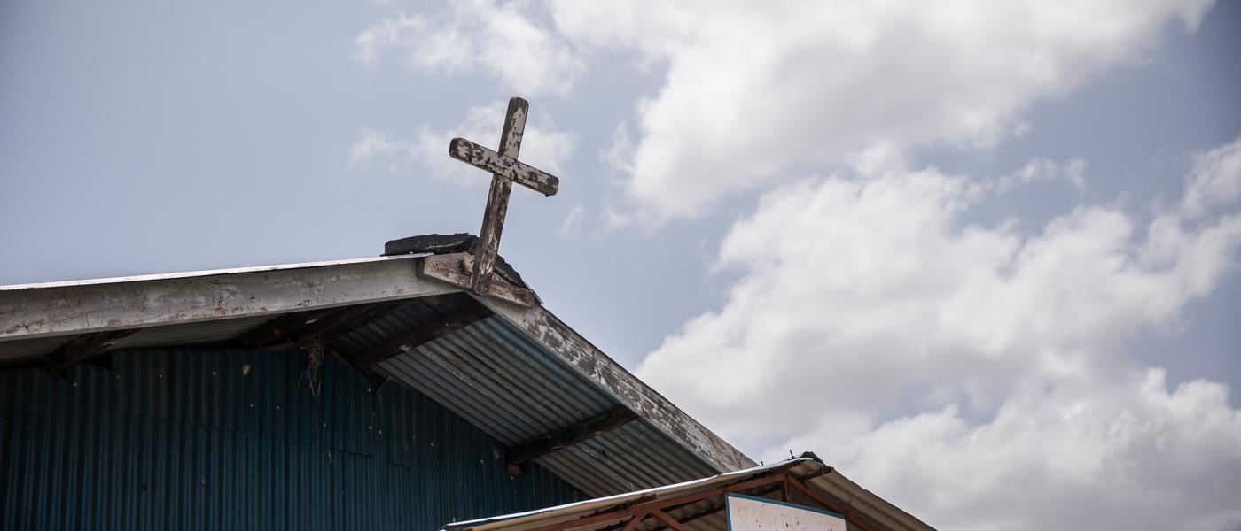 Ett kors på kyrktak mot blå himmel 