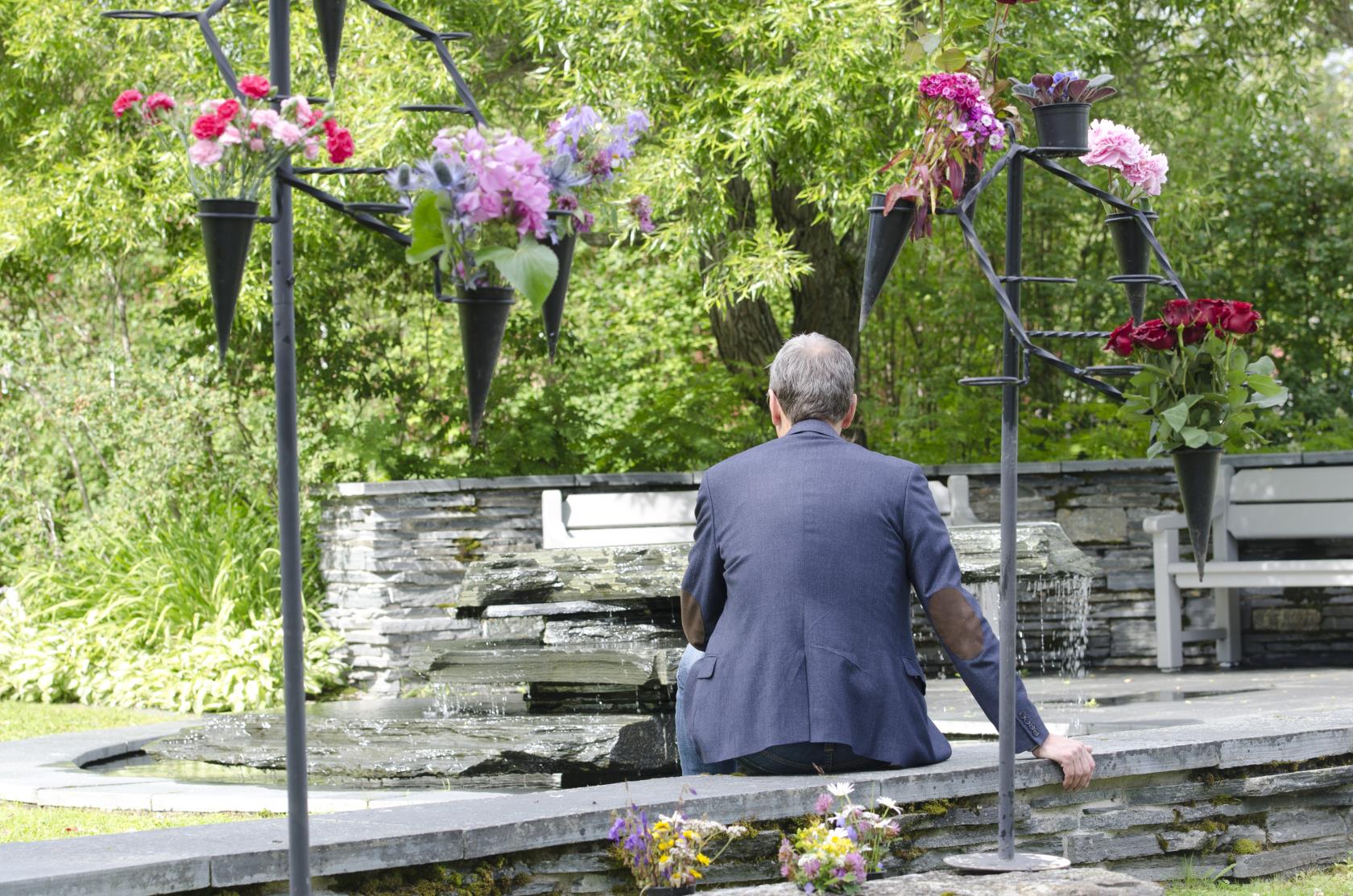 Man sittande vid minneslunden på Frösö kyrkogård.