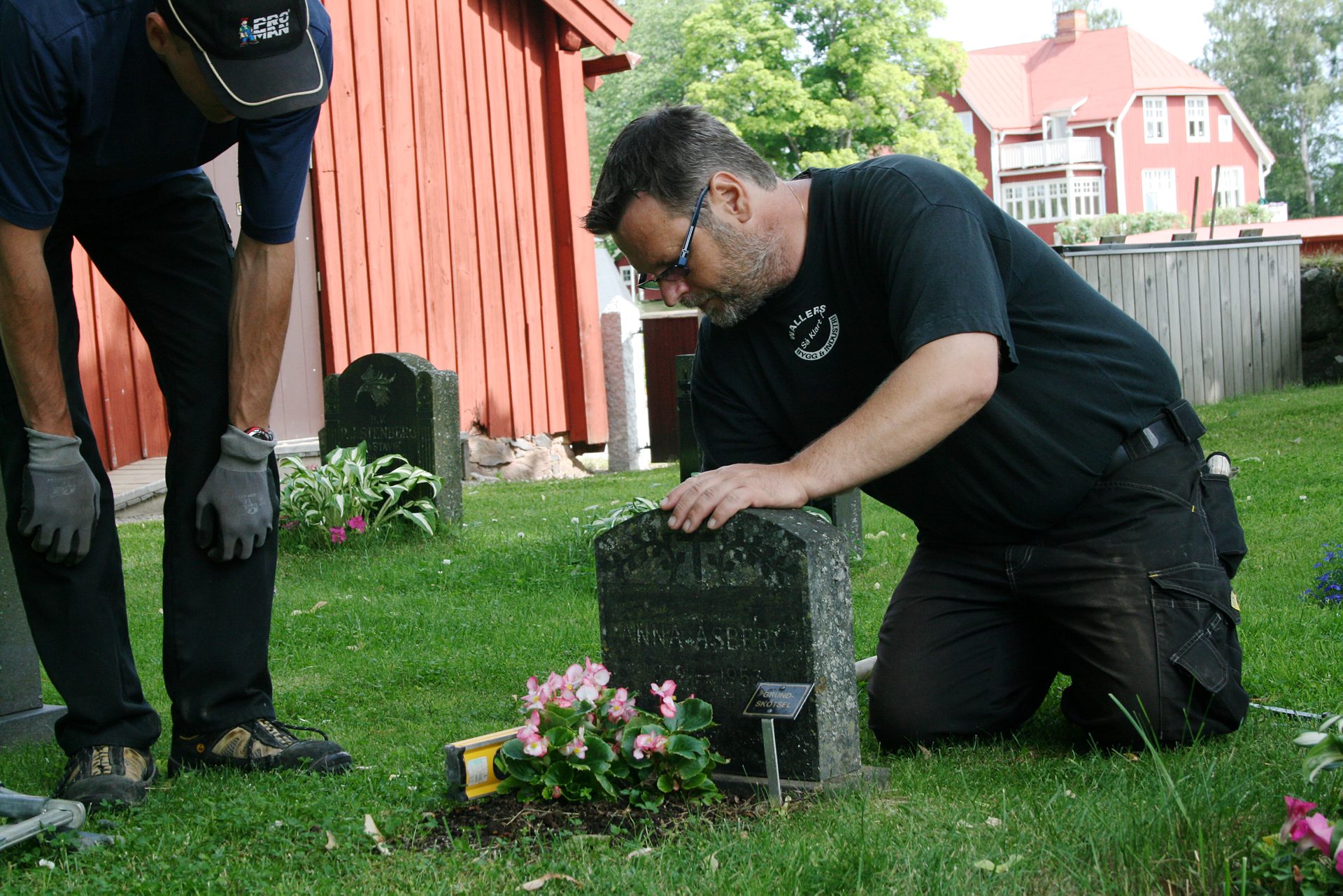 Kyrkogårdsarbetare stagar upp gravsten