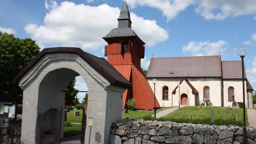 Ett valv,  ett klocktorn och Orkesta kyrkas huvudbyggnad, det är sommar