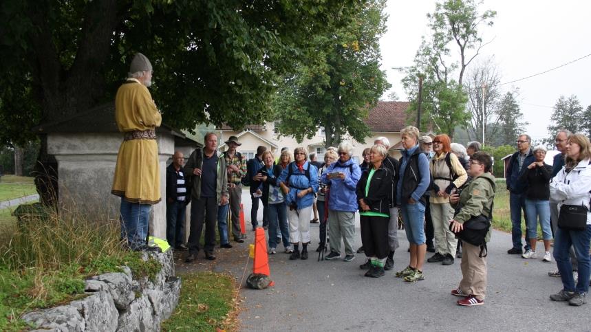 Ett antal personer som deltar i en vandring står och lyssnar när en guide berättar