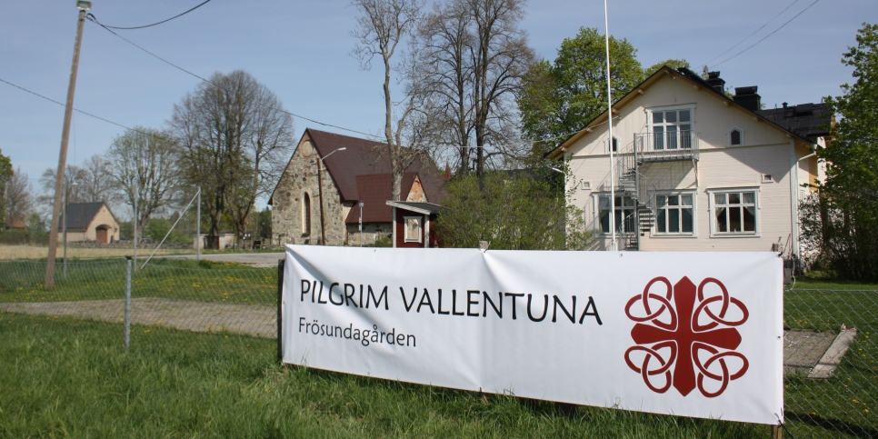 En banderoll på ett staket, med texten Pilgrim Vallentuna, Frösundagården