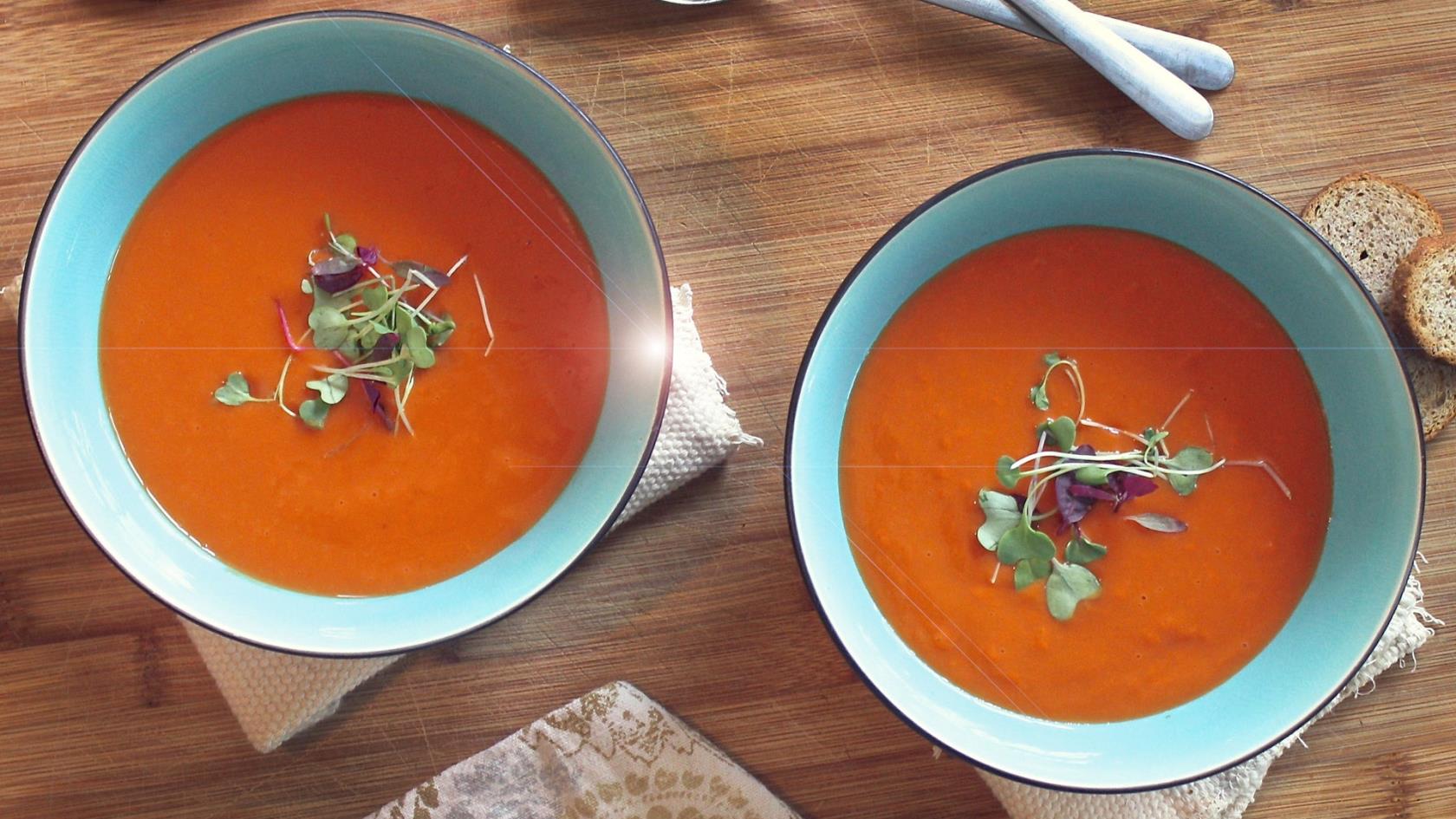 Två blåa tallrikar fyllda med krämig orange soppa.