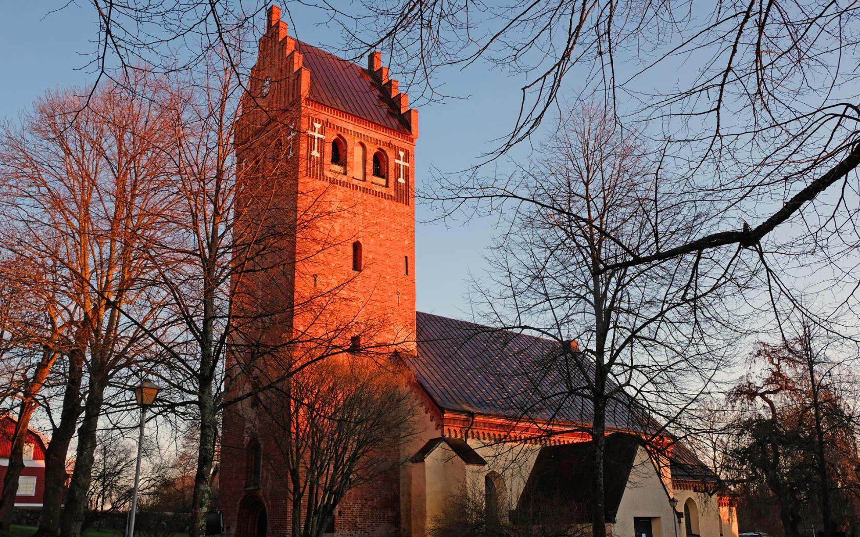 Torshälla kyrka. Solen ligger på tornet vilket ger en brandorange färg. 