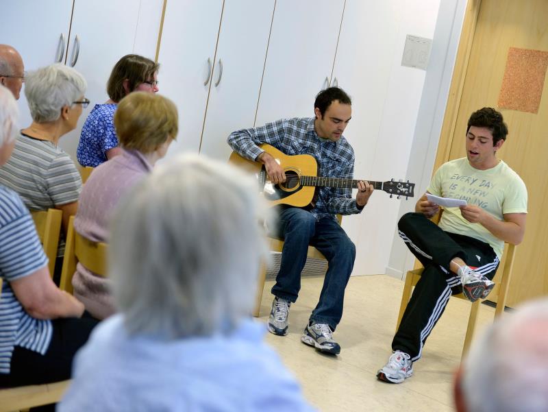 Två personer spelar gitarr och sjunger för en mindre publik