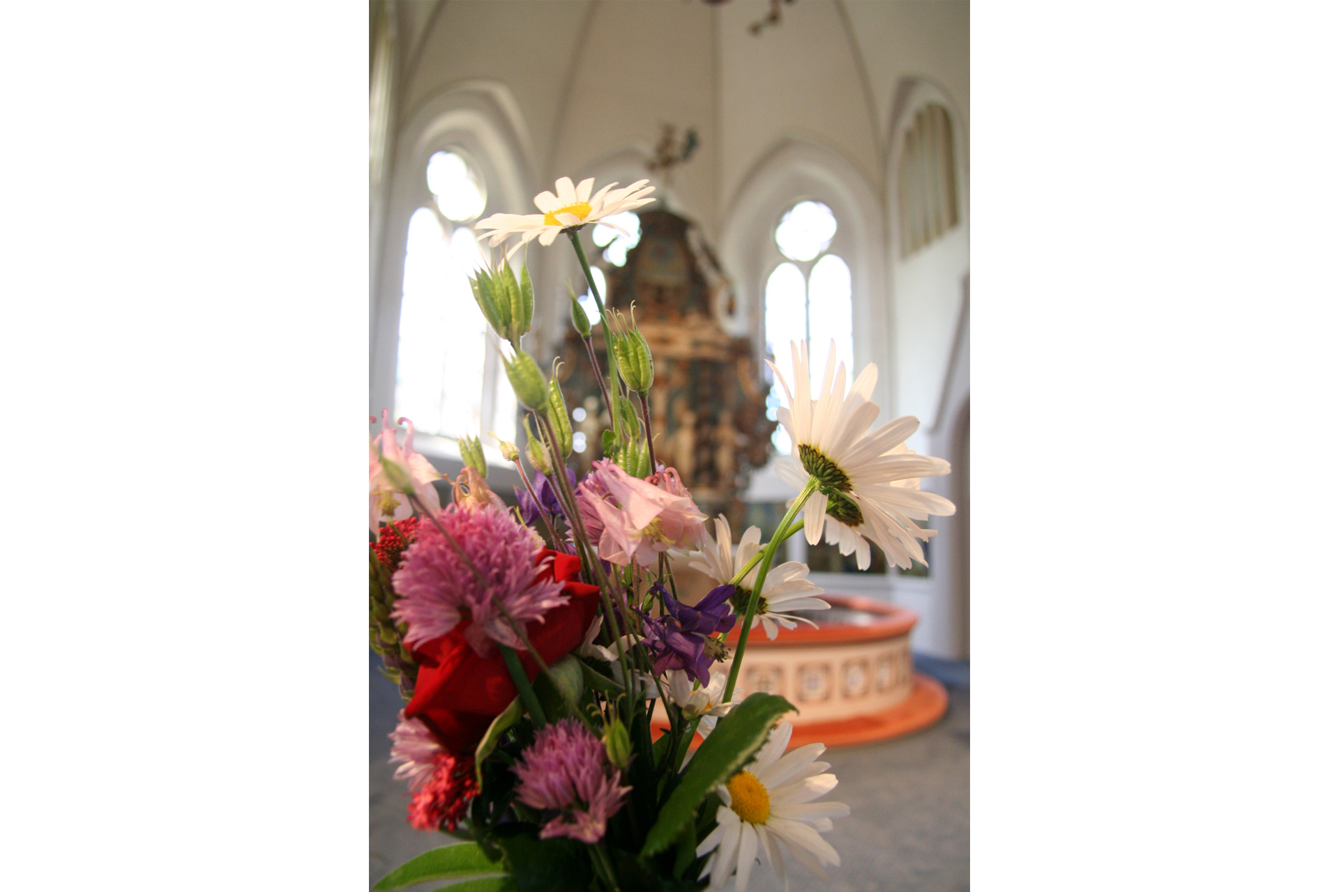 Blombukett i förgrunden framför altaret i Fässbergs kyrka