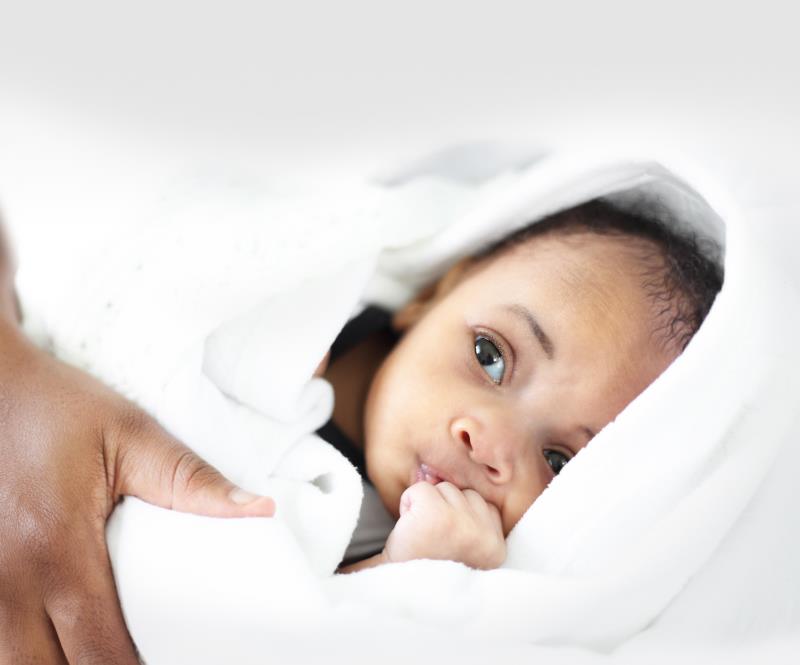 Nyfödd flicka invirad i en vit handduk. 