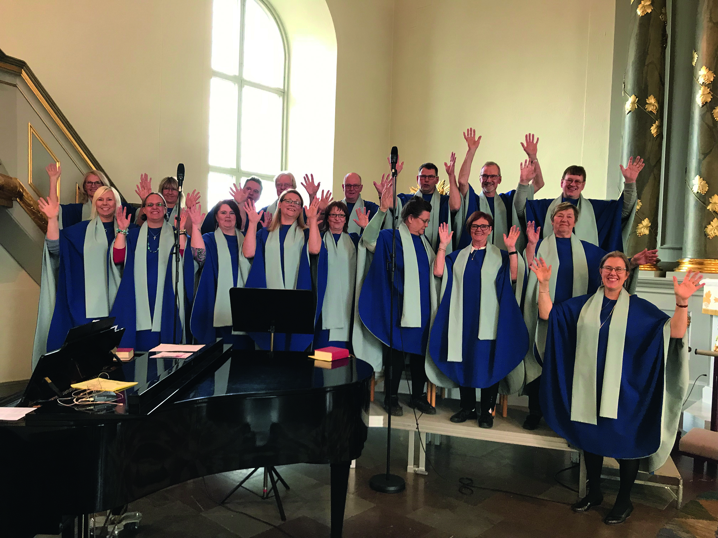 Glad gospelkör med händerna i luften, i kyrka