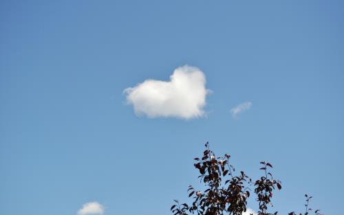 Ett moln har formen av ett hjärta på den blå himlen.