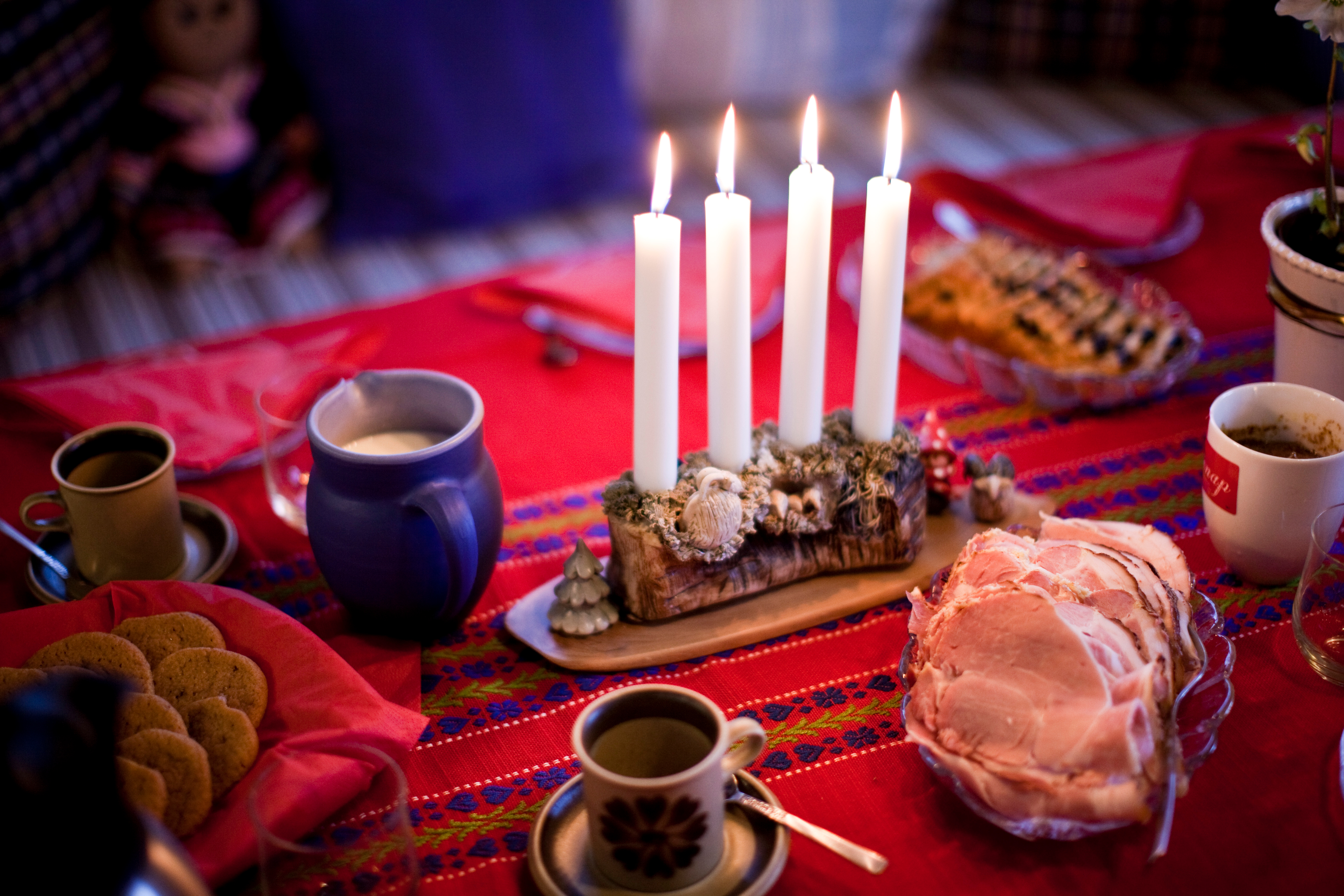 En adventsljusstake med alla ljus tända står på ett julbord.