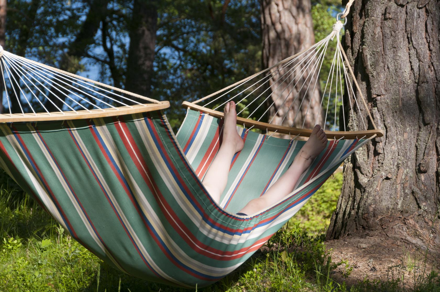 Någon ligger i en hängmatta i solen.