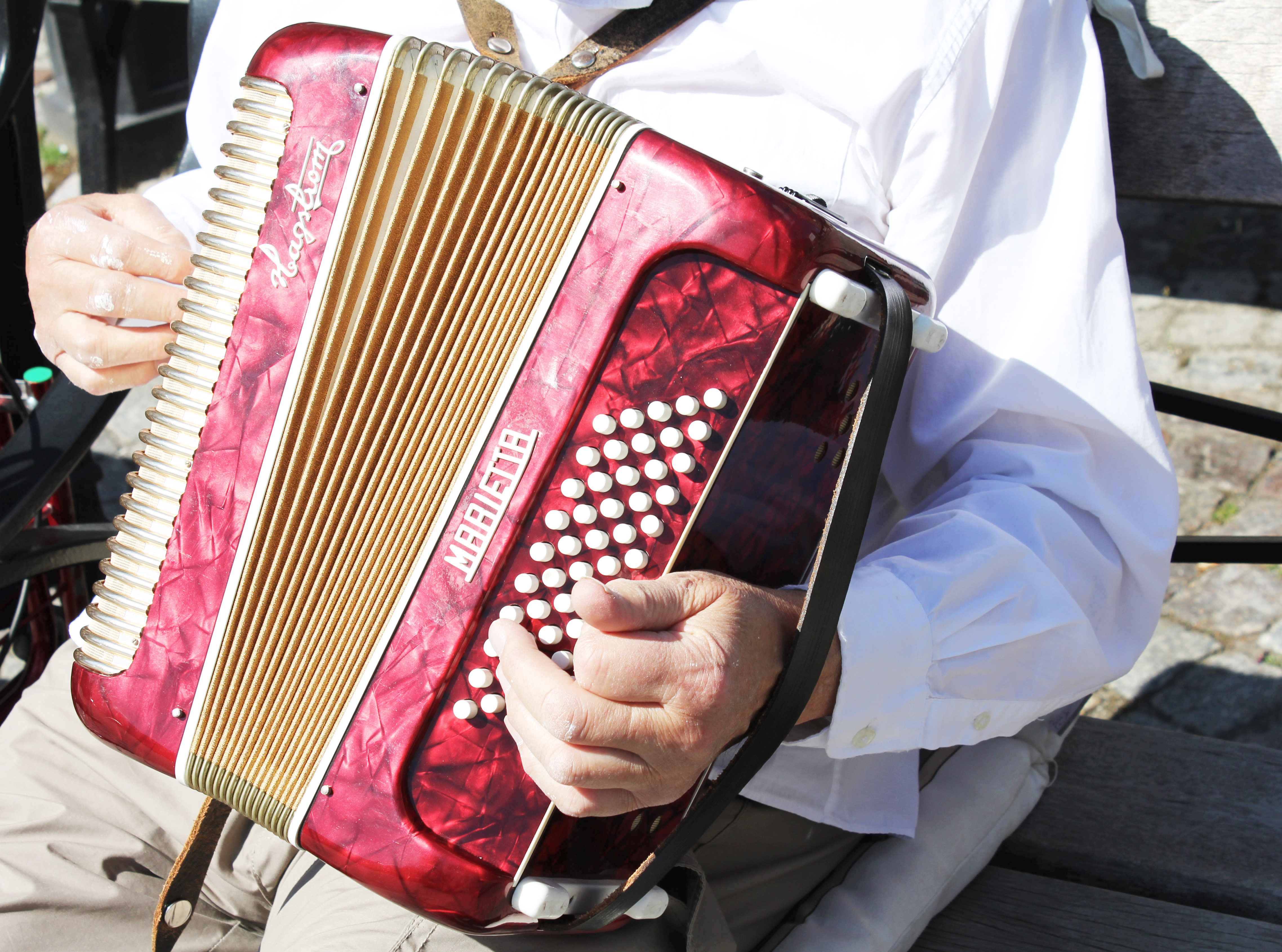 En musikant spelar dragspel utomhus.