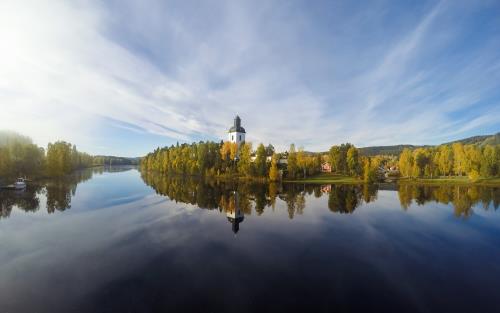 En kyrka vid vattnet reflekteras i den stilla vattenytan.