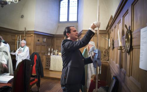 En kyrkvaktmästare putsar en biskopsstav i sakristian.