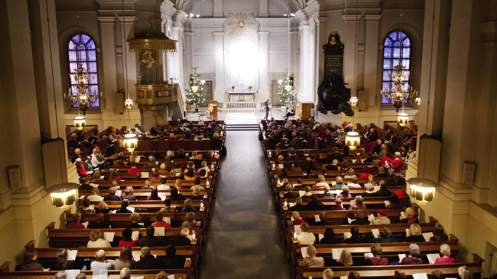 En kyrka full av besökare i bänkarna fotograferad från orgelläktaren.