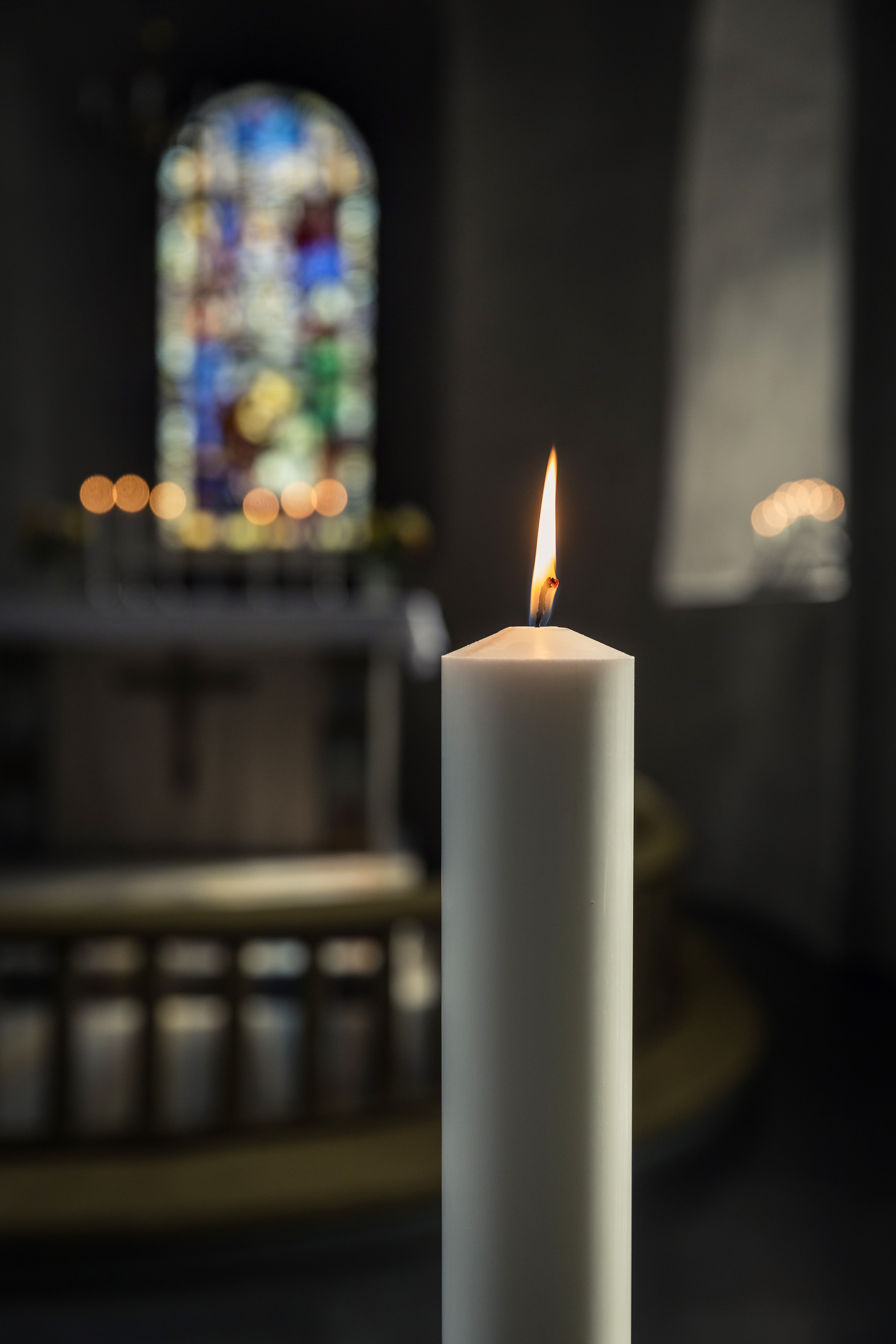 Ett tänt stearinljus i en kyrka.