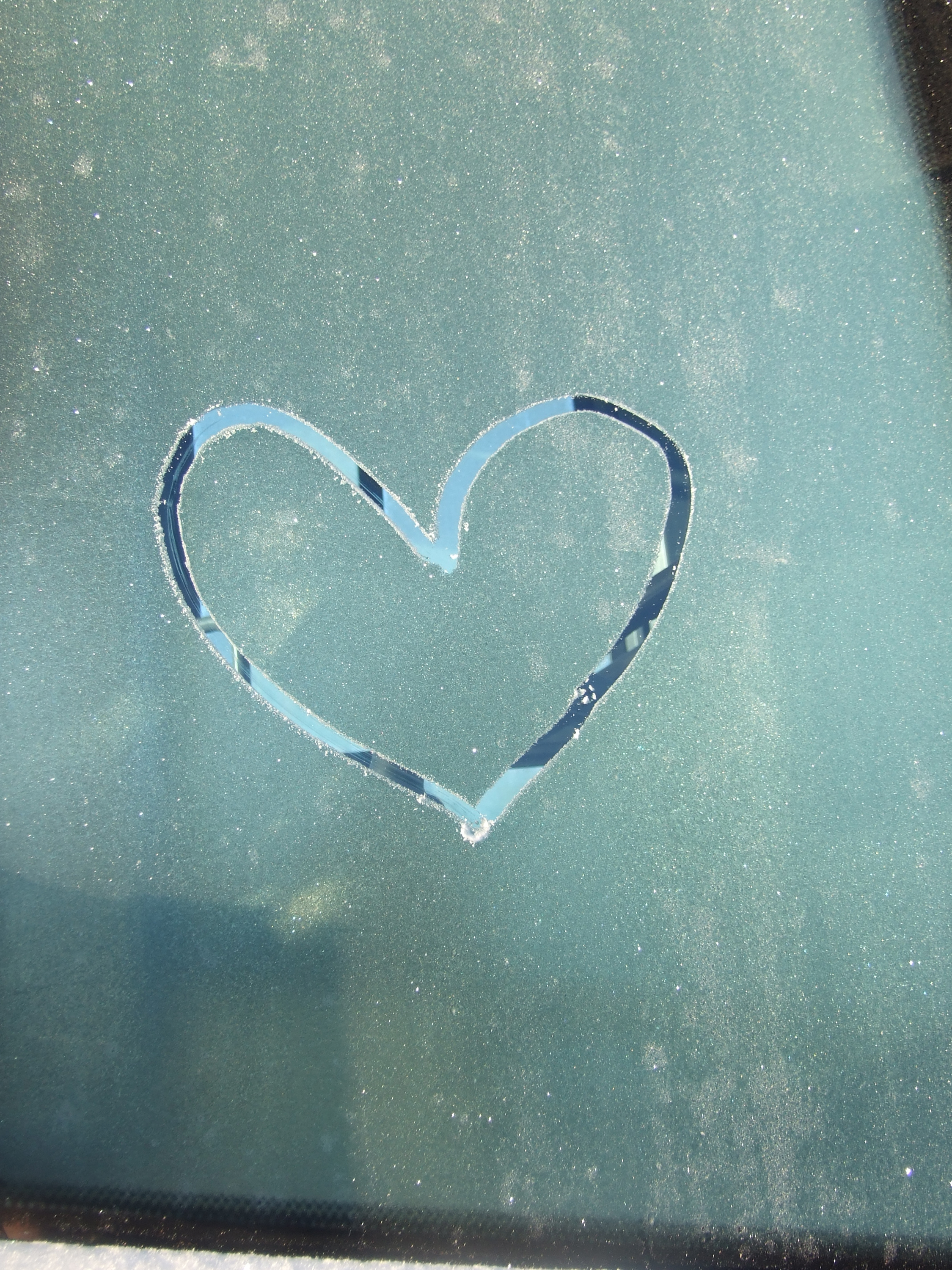 Någon har ritat ett hjärta med fingret på ett frostigt fönster.
