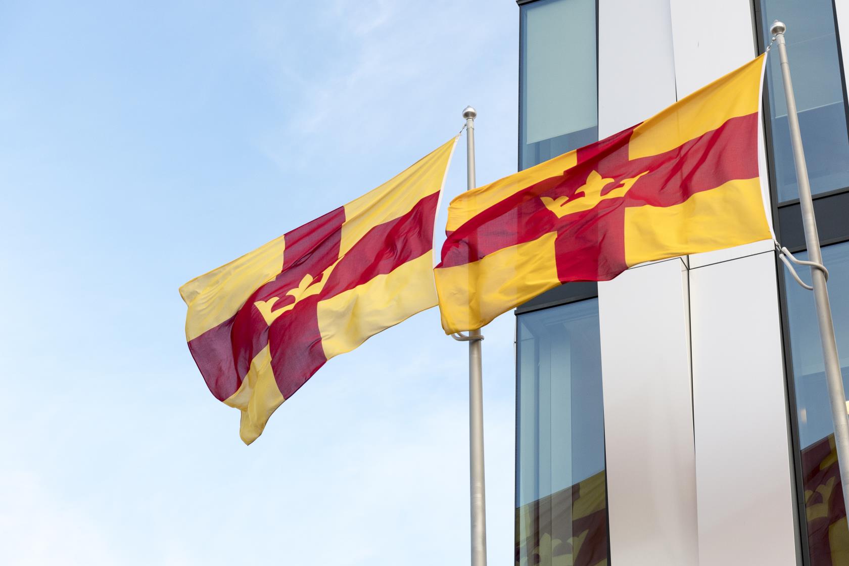 Två flaggstänger med Svenska kyrkans flagga utanför en byggnad.