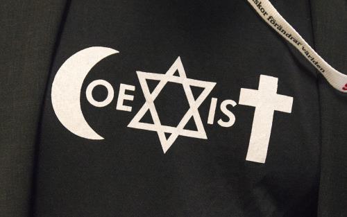 Symbolerna för islam, judendom och kristendom bildar tillsammans ordet Coexist på en tröja.