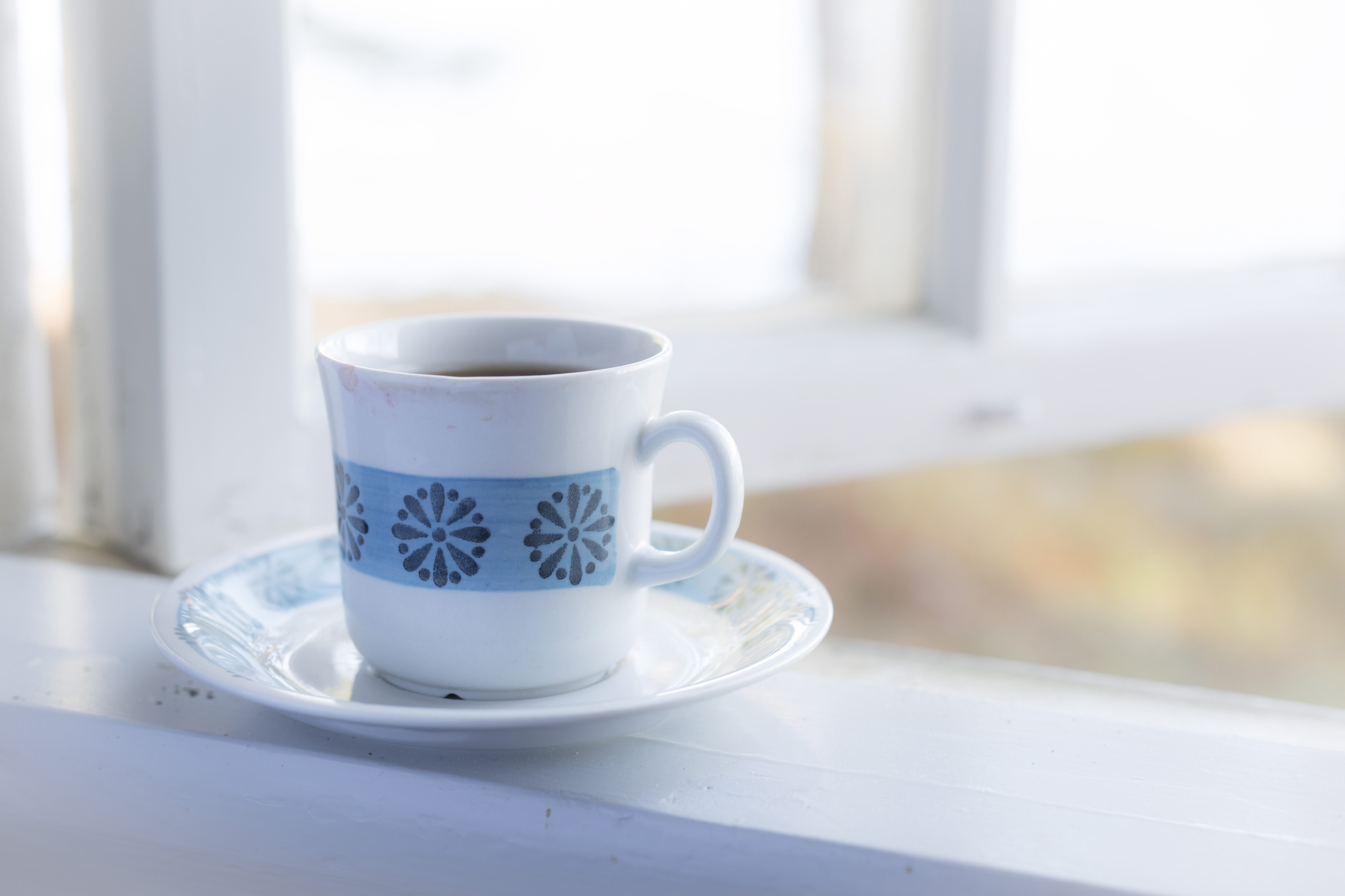 En kopp kaffe står i ett öppet fönster.