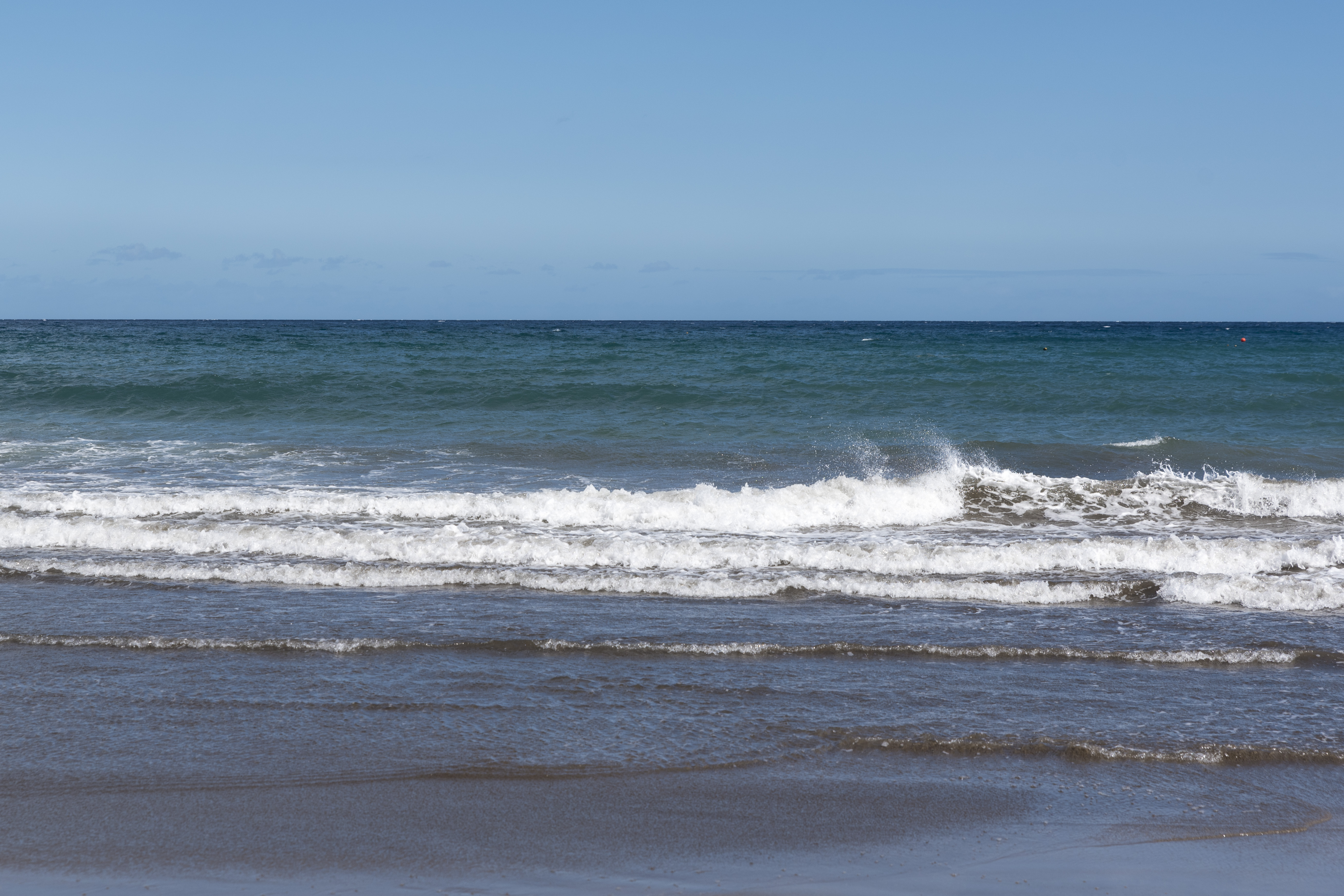 Vågor vid en sandstrand.