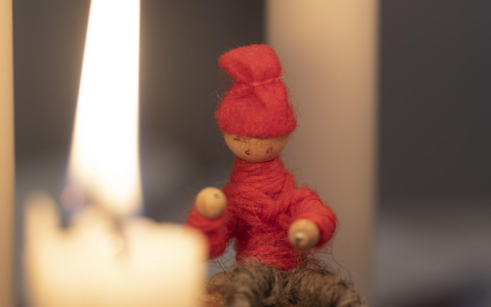 Ett tänt stearinljus och en liten tomte.