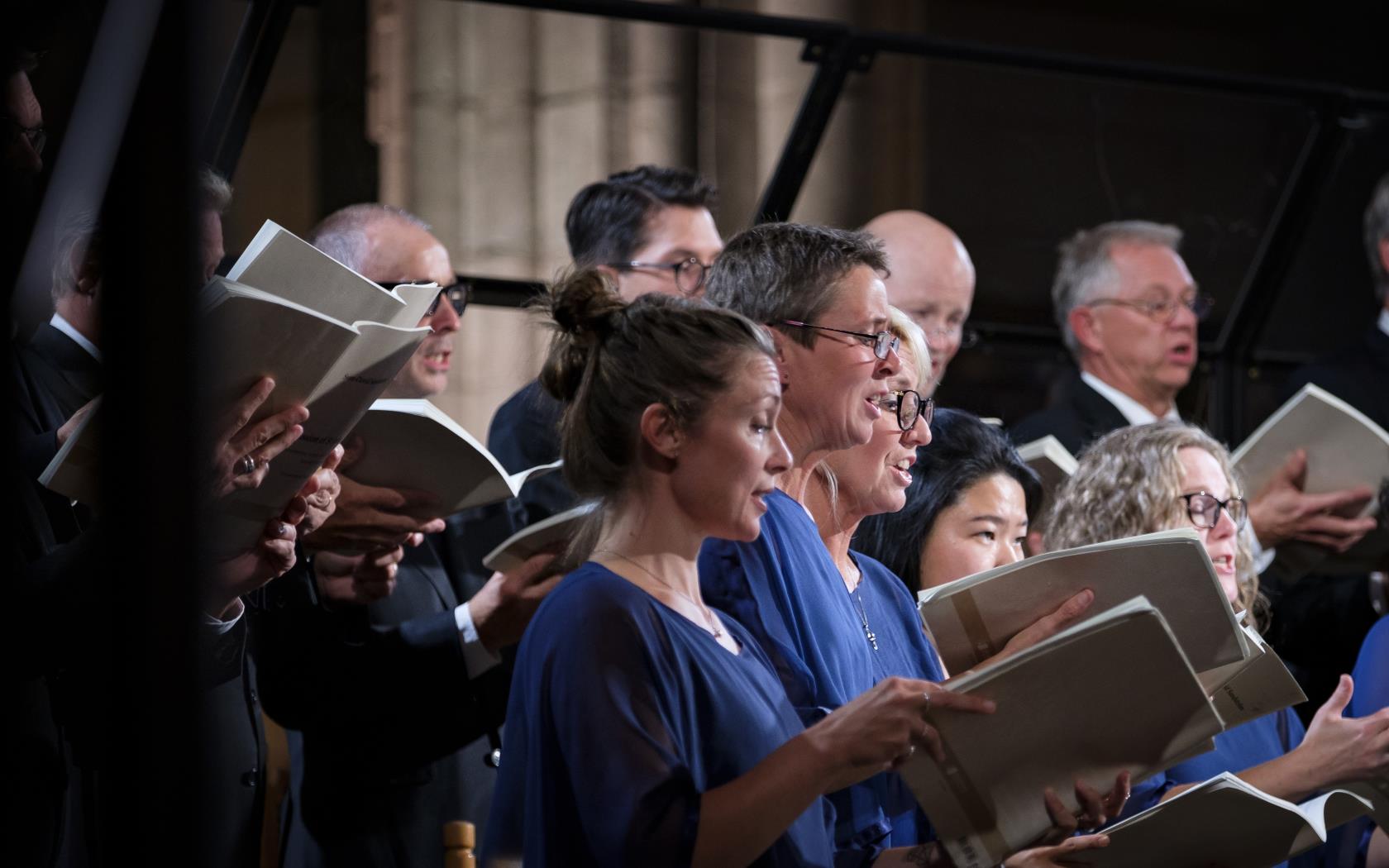 En blandad kyrkokör i matchande blå färger sjunger i Uppsala domkyrka.