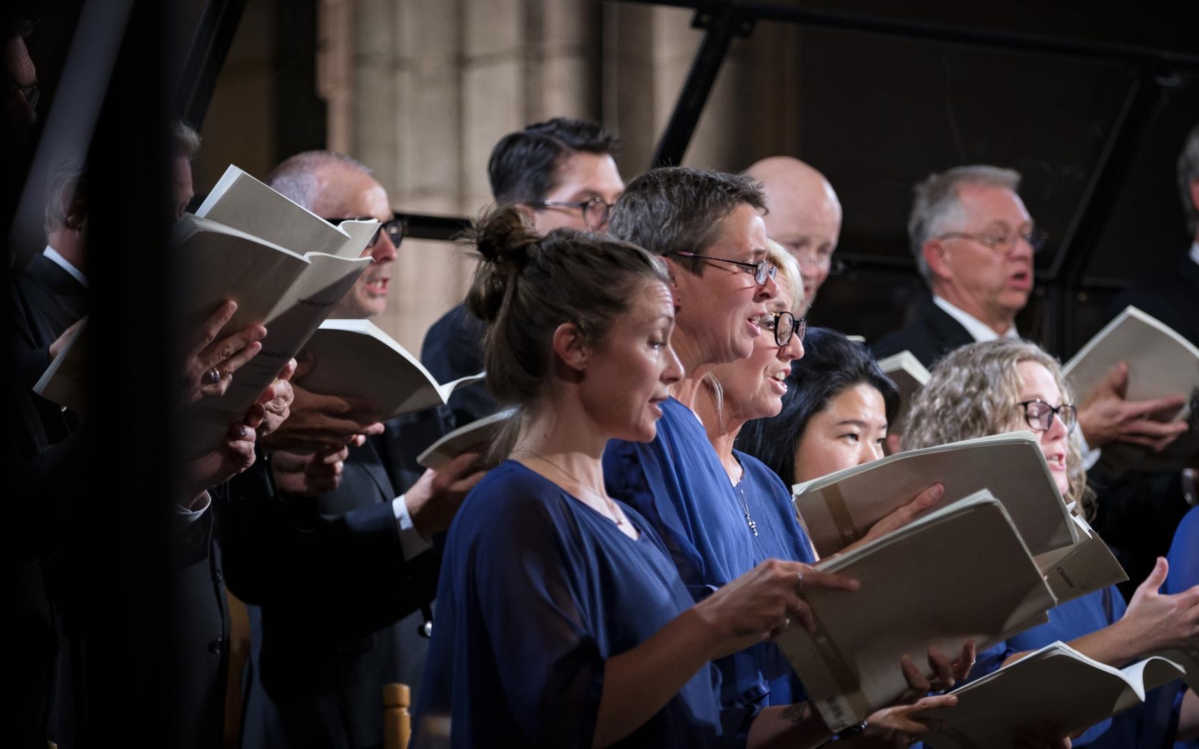 En blandad kyrkokör i matchande blå färger sjunger i Uppsala domkyrka.