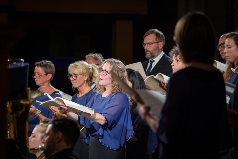 En blandad kyrkokör i matchande blå färger sjunger.