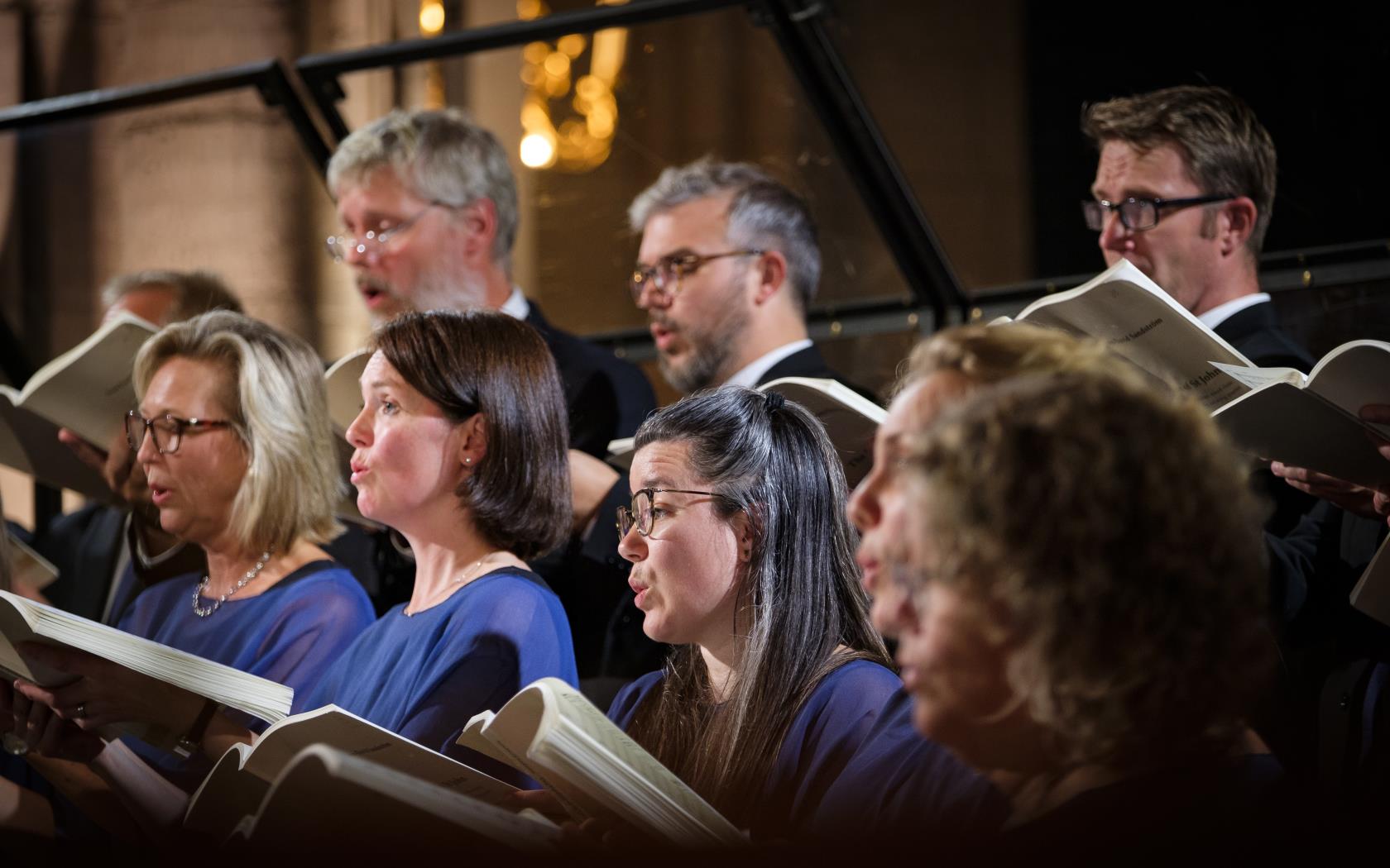 En blandad kyrkokör i matchande blå färger sjunger i Uppsala domkyrka.