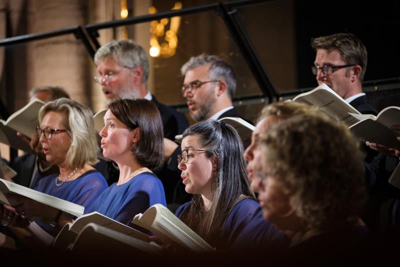 En blandad kyrkokör i matchande blå färger sjunger i Uppsala domkyrka.