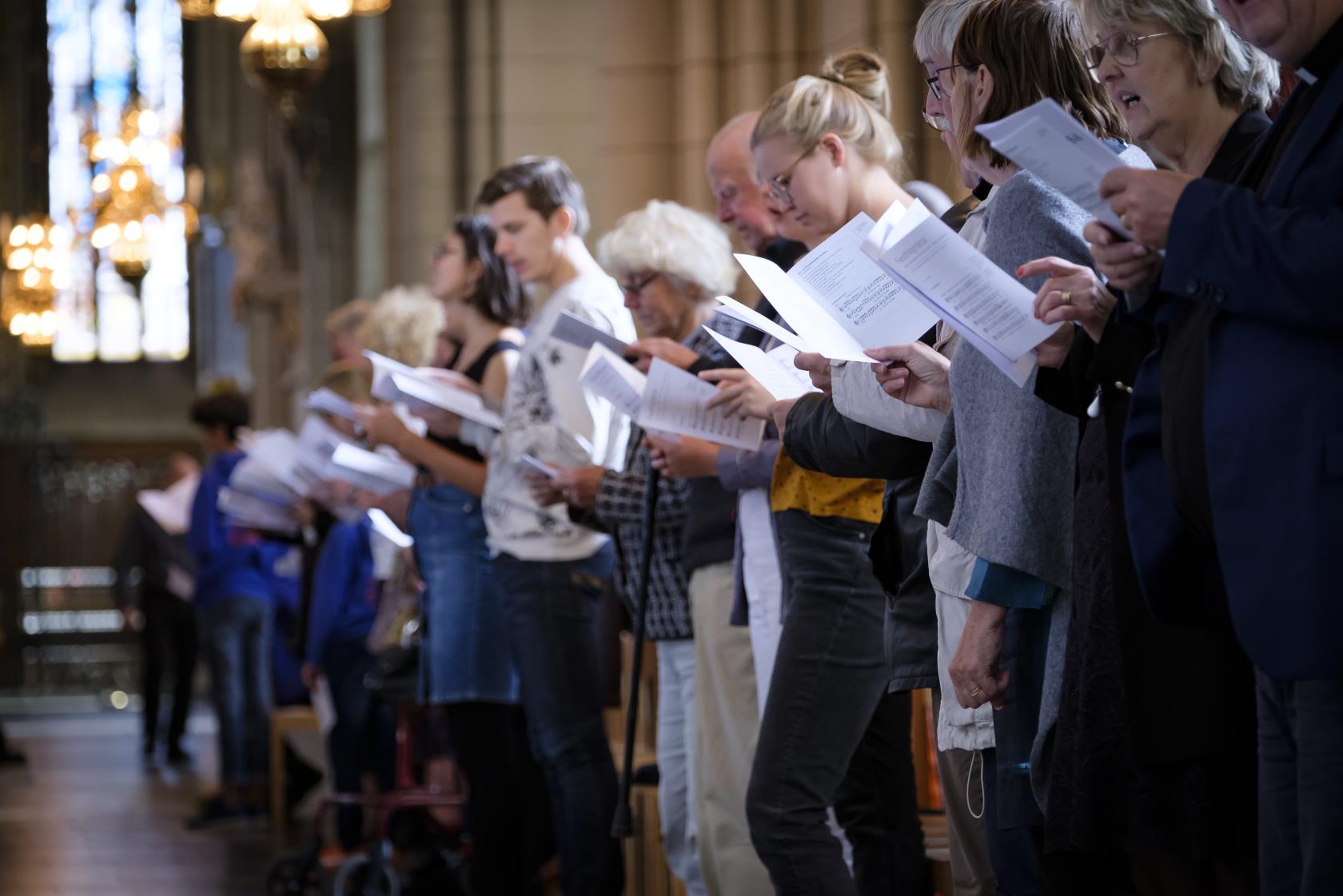 En rad människor står med sånghäften och sjunger i Uppsala domkyrka.