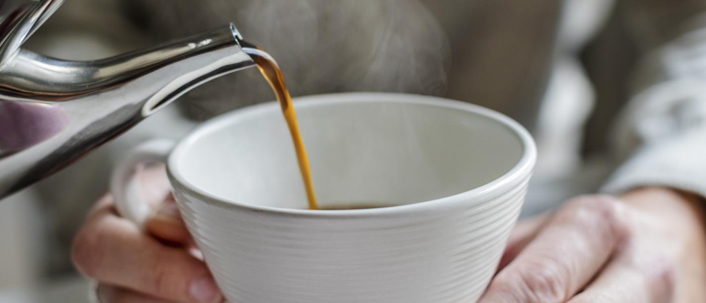 En person häller upp kaffe till någon som håller upp sin kopp.
