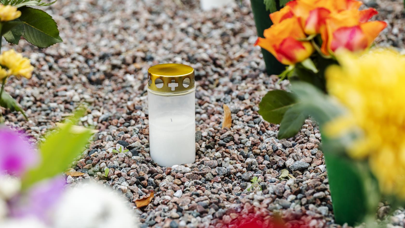 En massa blombuketter och gravljus står på en minneslund.